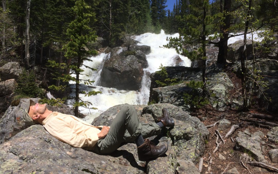 Scott Brown of Active Peace laying on a rock by a water fall